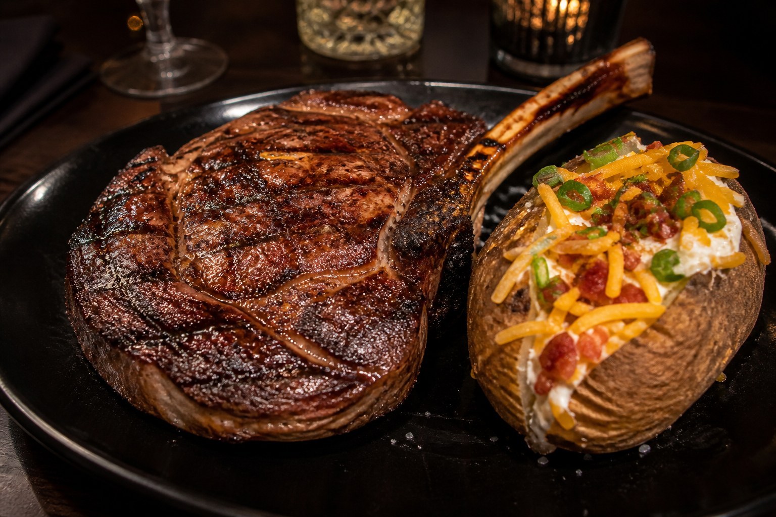 20 oz Outlaw Ribeye bone-in steak on black plate with loaded baked potato at LongHorn Steakhouse 2026